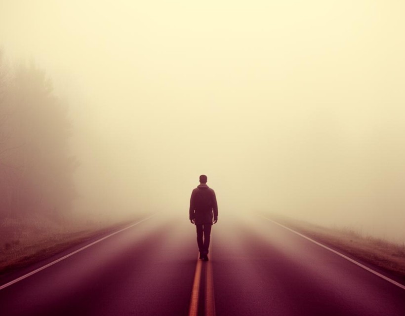 A woman walking alone on a misty path at dawn